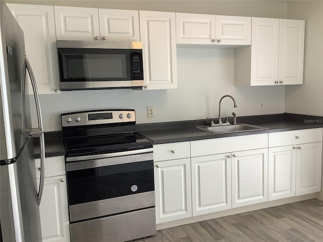 kitchen featuring white cabinetry, sink, light wood-type flooring, and appliances with stainless steel finishes