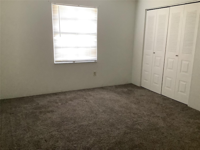 unfurnished bedroom featuring a closet and dark colored carpet