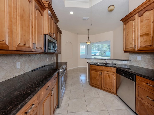 kitchen with sink, stainless steel appliances, tasteful backsplash, dark stone countertops, and pendant lighting