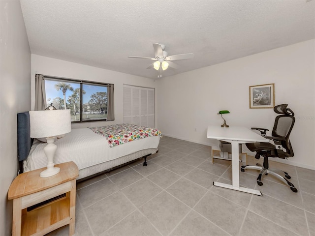 tiled bedroom with ceiling fan, a textured ceiling, and a closet