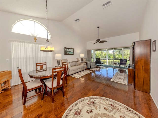 dining room with dark hardwood / wood-style floors, ceiling fan, and high vaulted ceiling