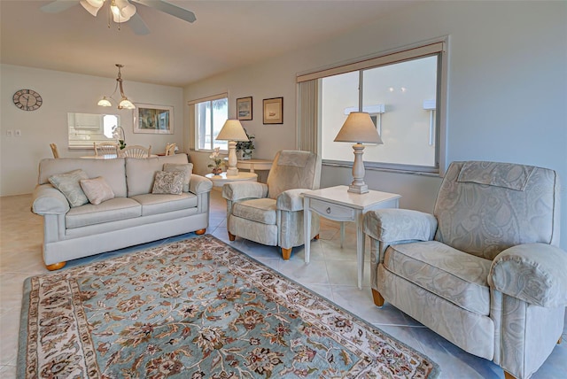 tiled living room with ceiling fan with notable chandelier