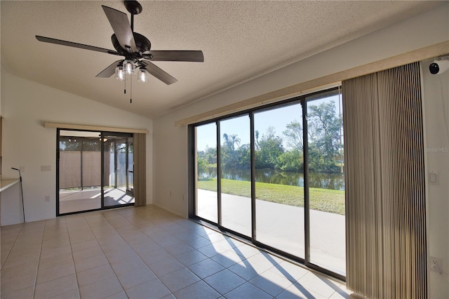 tiled empty room featuring a water view, a wealth of natural light, lofted ceiling, and ceiling fan