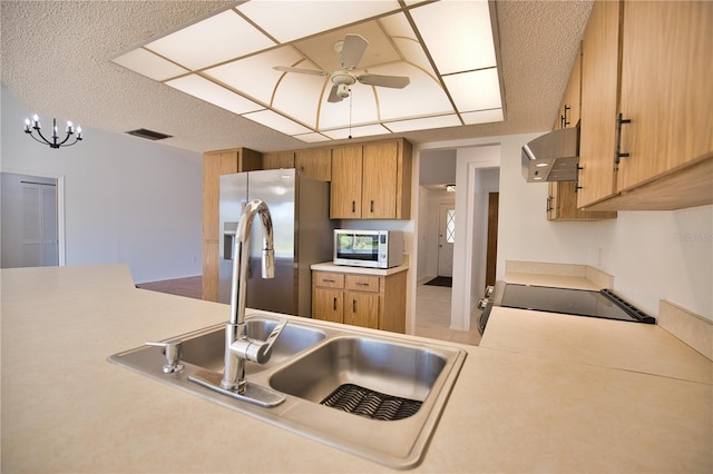 kitchen featuring stainless steel fridge, ceiling fan with notable chandelier, sink, black range, and range hood