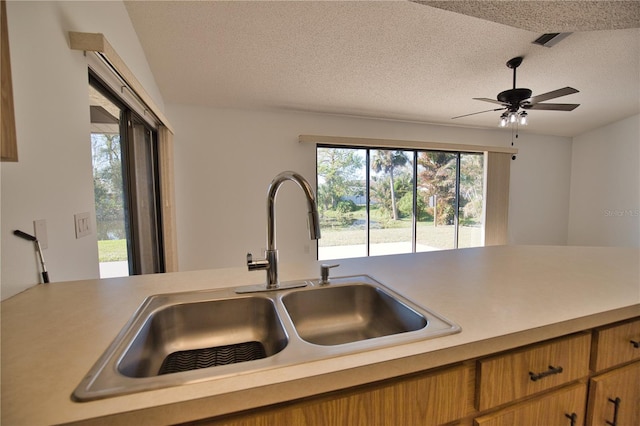 kitchen with a textured ceiling, ceiling fan, and sink