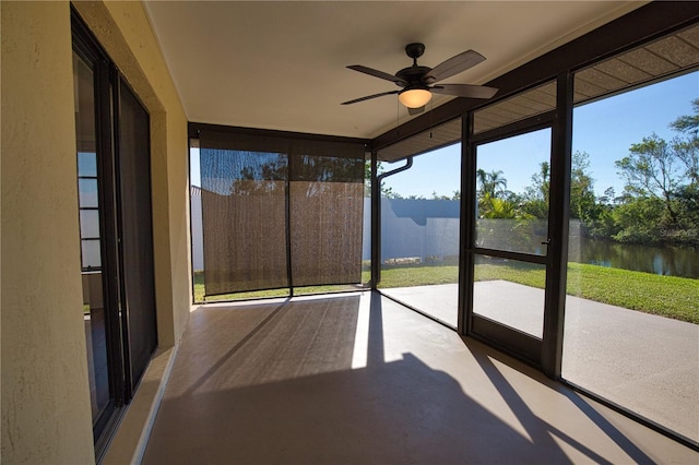 unfurnished sunroom with ceiling fan and a water view