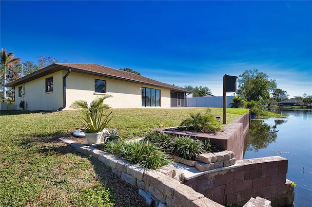 view of property exterior featuring a water view and a lawn