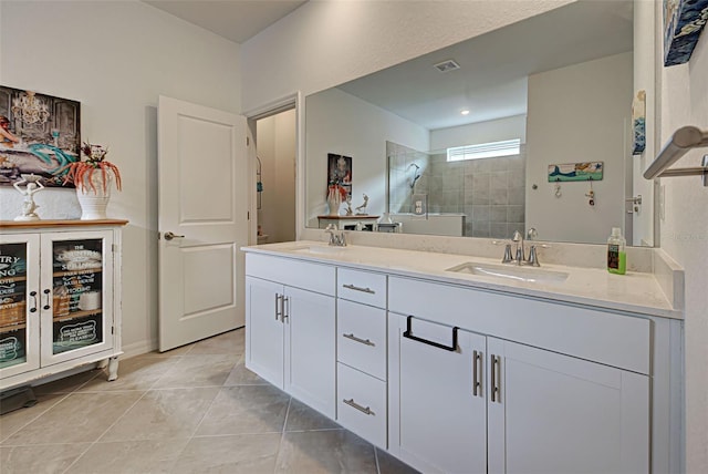 bathroom with tile patterned flooring, vanity, and tiled shower