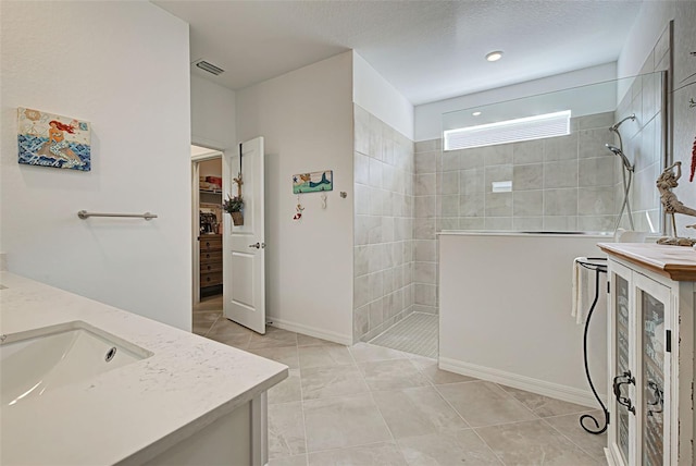 bathroom featuring tile patterned flooring, vanity, and tiled shower