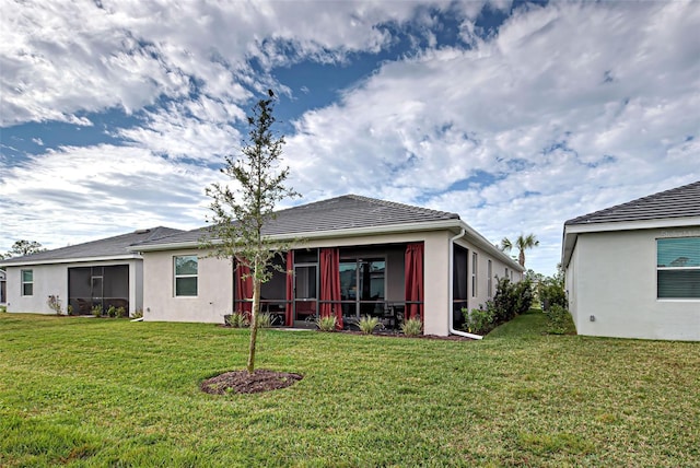 rear view of house featuring a sunroom and a yard