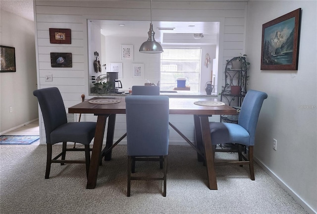 carpeted dining room featuring wooden walls