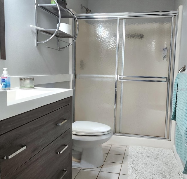 bathroom with tile patterned flooring, vanity, toilet, and walk in shower