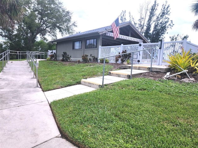 view of front of home with a deck and a front lawn