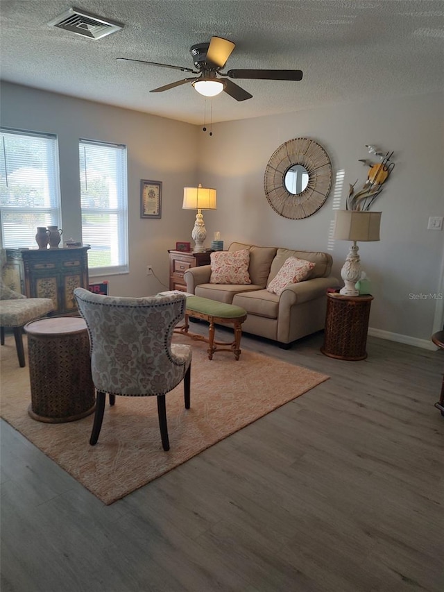 living room with a textured ceiling, dark hardwood / wood-style flooring, and ceiling fan