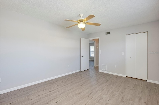 unfurnished bedroom featuring ceiling fan, a closet, a textured ceiling, and light wood-type flooring