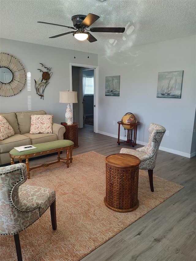 living room featuring ceiling fan, a textured ceiling, and dark wood-type flooring