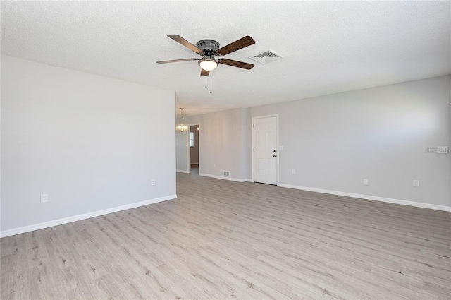 spare room with ceiling fan with notable chandelier, light hardwood / wood-style floors, and a textured ceiling