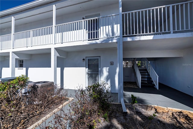 doorway to property with cooling unit, a balcony, and stucco siding