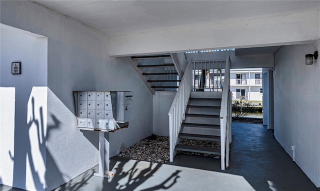 staircase featuring concrete floors and a mail area