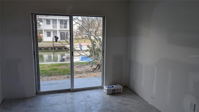 doorway with a water view and light tile patterned floors