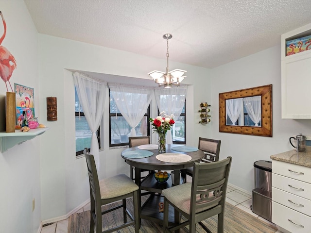 tiled dining room featuring a textured ceiling and an inviting chandelier