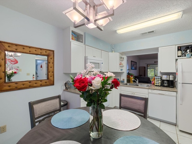 dining room featuring a textured ceiling, a notable chandelier, light tile patterned flooring, and sink