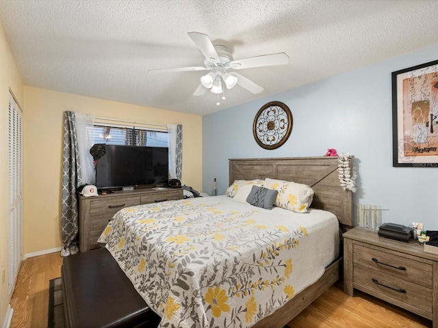 bedroom featuring ceiling fan, light hardwood / wood-style floors, and a textured ceiling