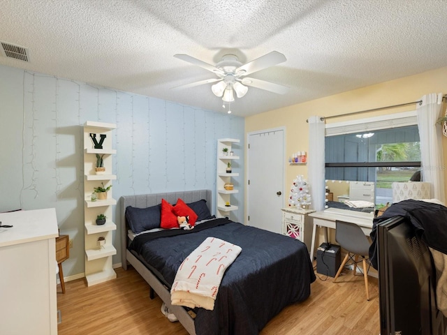 bedroom featuring ceiling fan, light hardwood / wood-style flooring, and a textured ceiling