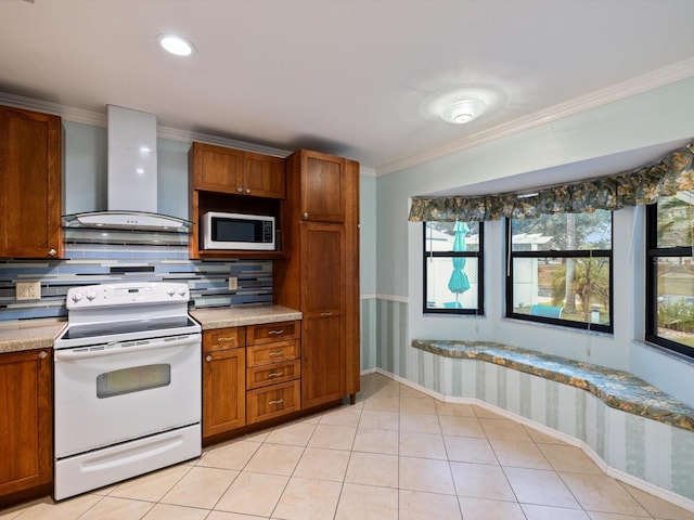 kitchen with white appliances, wall chimney range hood, crown molding, and a wealth of natural light