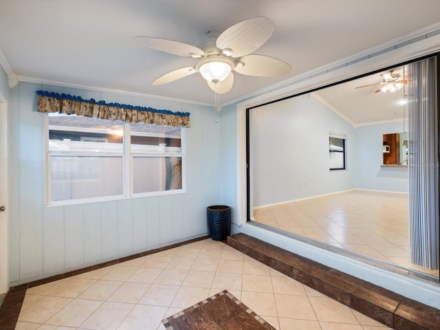 empty room featuring crown molding, light tile patterned floors, vaulted ceiling, and ceiling fan