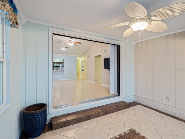 empty room featuring light tile patterned floors, vaulted ceiling, ceiling fan, and ornamental molding