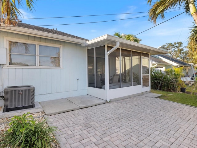 rear view of house with a sunroom, a patio, and central AC