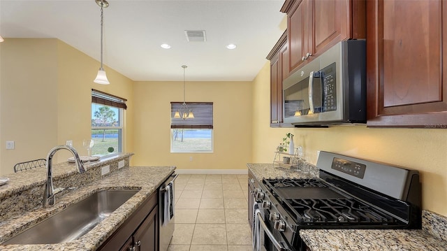 kitchen with sink, hanging light fixtures, stainless steel appliances, light stone counters, and light tile patterned floors