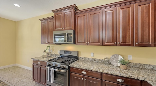 kitchen featuring light tile patterned flooring, light stone counters, and stainless steel appliances