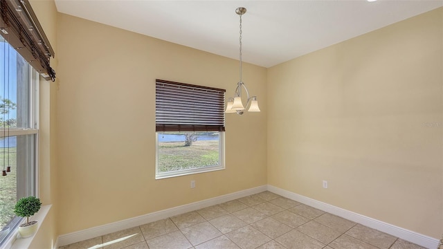 tiled empty room featuring an inviting chandelier