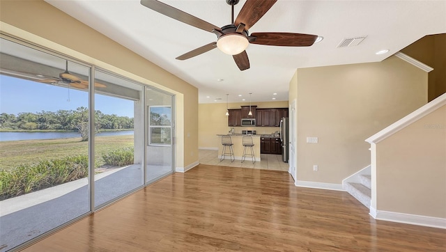 living room with a water view, light hardwood / wood-style flooring, and ceiling fan