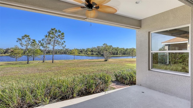 view of yard with ceiling fan and a water view