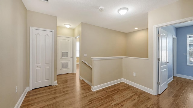 corridor with wood-type flooring and a textured ceiling