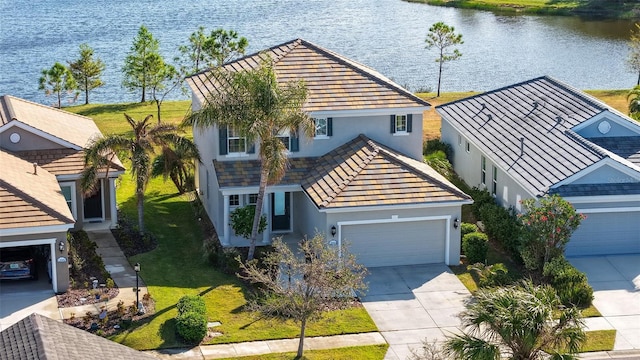 view of front of house with a garage, a water view, and a front lawn