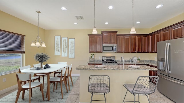 kitchen featuring pendant lighting, a kitchen island with sink, a kitchen breakfast bar, a notable chandelier, and stainless steel appliances