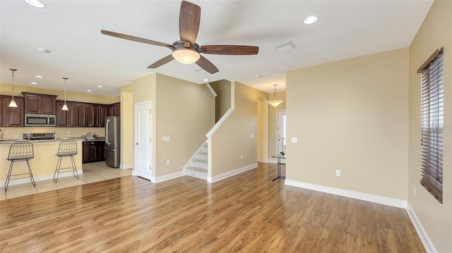 unfurnished living room featuring ceiling fan and light wood-type flooring