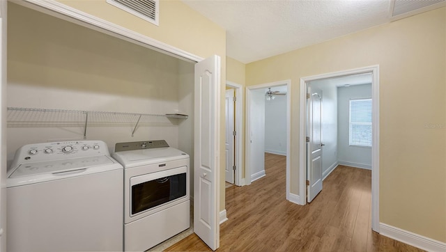 laundry room featuring ceiling fan, independent washer and dryer, light wood-type flooring, and a textured ceiling