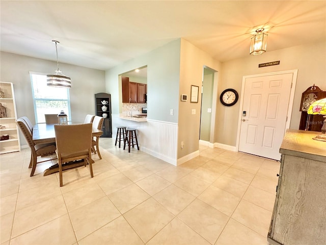 tiled dining room featuring a notable chandelier and sink