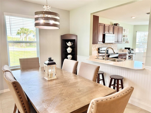 dining area featuring a healthy amount of sunlight, light tile patterned floors, and sink