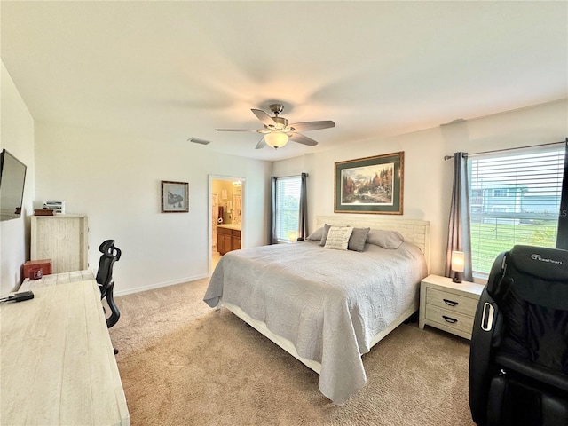 bedroom with ceiling fan, light carpet, connected bathroom, and multiple windows