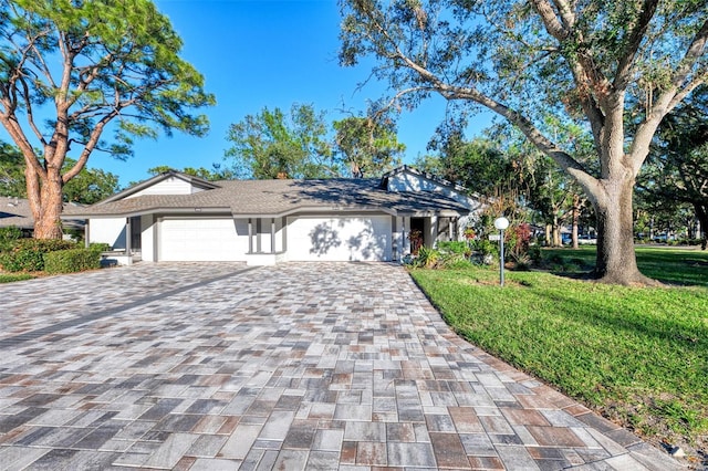 ranch-style home featuring a garage and a front lawn