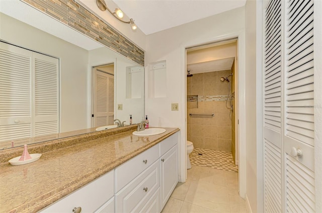 bathroom featuring tile patterned flooring, vanity, tiled shower, and toilet