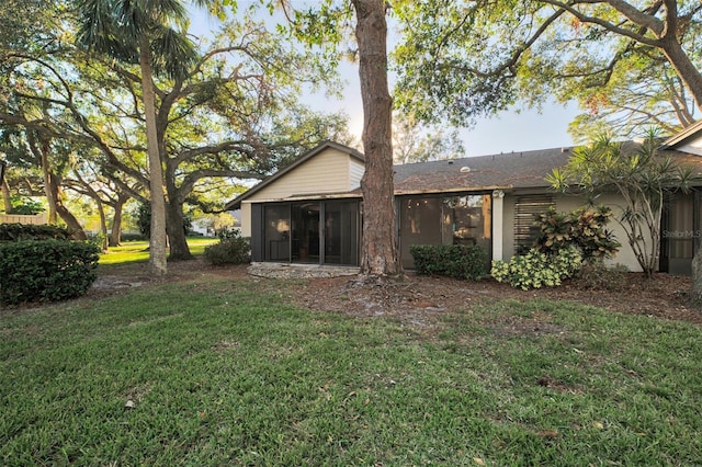 back of property with a lawn and a sunroom