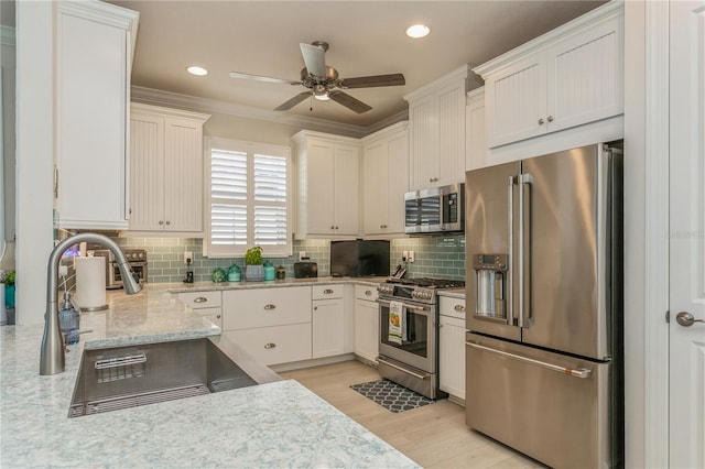 kitchen with light stone countertops, ceiling fan, sink, white cabinetry, and premium appliances