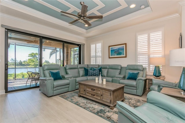 living room with ornamental molding, ceiling fan, a tray ceiling, and light hardwood / wood-style flooring